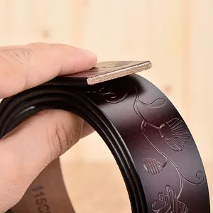 Vue détaillée d'une ceinture en cuir marron foncé avec motifs floraux gaufrés et marquage 115cm