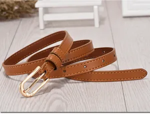 Close-up of brown leather skinny belt featuring a gold buckle with heart engraving