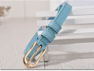 Detail of light blue leather belt with gold metal buckle featuring heart engravings
