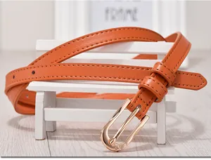 Detail of bright orange skinny belt with gold buckle on a white decorative bench