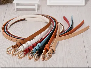 Collection of colorful slim leather belts for women with gold oval buckles on wood surface