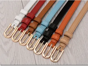 Flat lay of colorful slim women's belts with heart engraved golden metal buckles