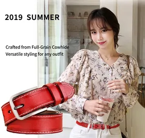 Détail de ceinture en cuir rouge avec coutures blanches et boucle à ardillon argentée