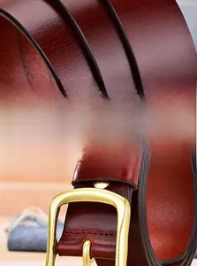 Detailed macro of red-brown genuine leather belt showing alloy buckle and fine stitching