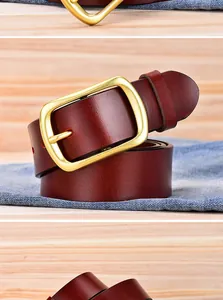 Macro detail of genuine leather belt with matte gold square buckle on denim background
