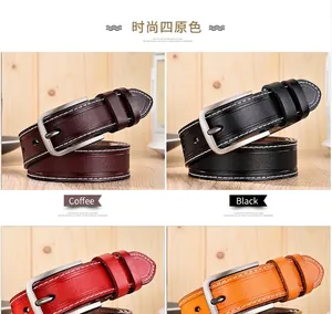 Détail de quatre ceintures en cuir colorées avec boucles en métal sur fond bois