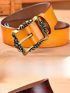Detail of vintage embossed leather belt featuring floral patterns and carved metal buckle