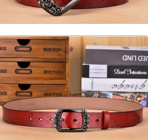 Détail de la ceinture en cuir rouge avec gaufrage papillon et boucle creuse vintage