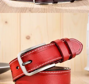 Détail macro d'une ceinture en cuir rouge avec coutures contrastées et boucle en métal argent