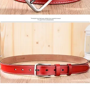 Détail d'une ceinture en cuir rouge avec boucle argentée et doubles coutures blanches