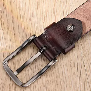 Détail d'une ceinture en cuir marron rougeâtre avec boucle à ardillon argentée brossée