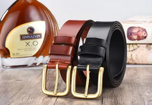Brown and black genuine leather men's belts with matte gold pin buckles on a wooden desk