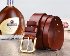 Detail of red-brown genuine leather belt with matte gold buckle next to wine bottle