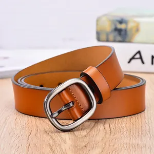 Brown leather belt for women featuring a round matte silver buckle on a wooden surface