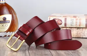 Detail of genuine leather belt with brass buckle next to vintage books and a bottle