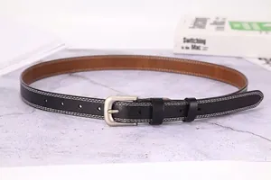 Detail of black leather belt with white stitching and silver matte needle buckle