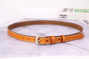 Detail of camel leather belt with fine stitching and brushed metal pin buckle on marble