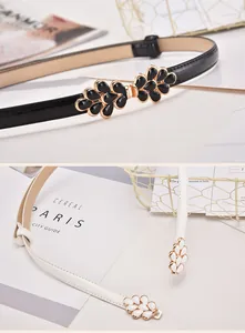 Detail of elegant leaf-shaped metal buckles on black and white thin belts for women