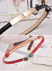 Close-up of narrow black and red glossy belts with decorative rhinestone buckles