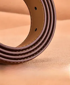 Vue macro d'une ceinture en cuir marron avec double surpiqûre beige et bords huilés