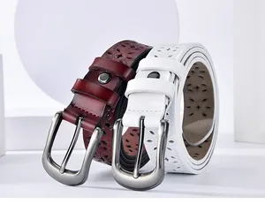 Detail of hollow floral pattern on burgundy and white leather belts with matte buckles