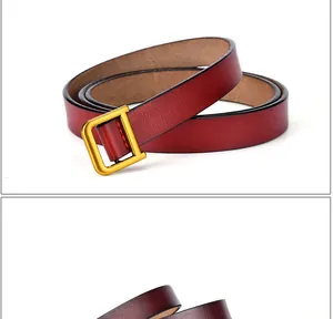 Détail d'une ceinture fine en cuir rouge avec boucle carrée dorée et finition de bord noir