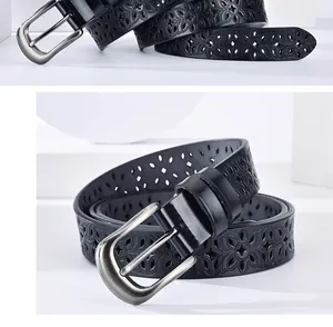 Detailed macro view of black leather belt featuring floral hollowed-out patterns and buckle