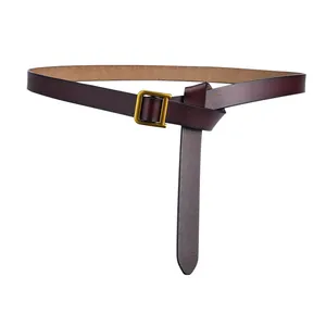 Détail d'une fine ceinture en cuir marron foncé avec boucle en D dorée mate et texture fine