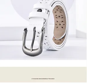 Macro detail of white leather belt with floral cut-outs and brushed horseshoe buckle