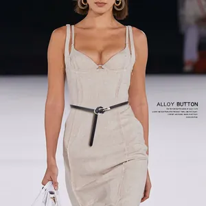 Detail of slim black leather belt with silver U-shaped buckle on a beige dress
