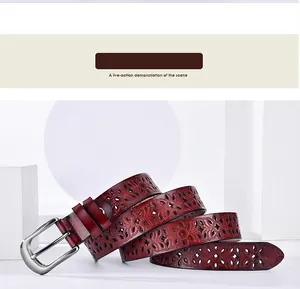 Detail of reddish-brown leather belt featuring intricate hollowed flower carvings and metal buckle