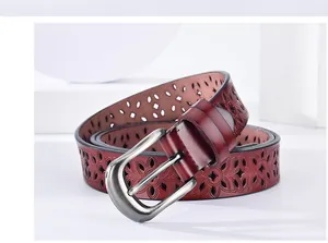 Close-up of dark red leather belt featuring elegant floral cutouts and silver pin buckle