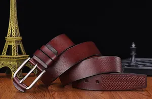 Detail of dark mahogany leather belt with chevron texture on a rustic wooden desk