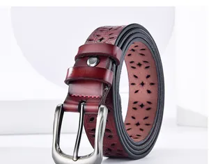 Detail of burgundy leather belt with laser-cut floral patterns and silver buckle