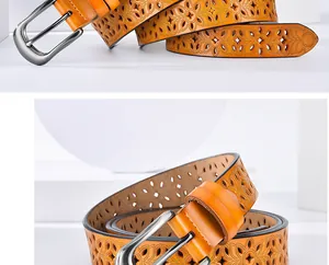 Detail of orange leather belt featuring laser-cut floral patterns and silver buckle