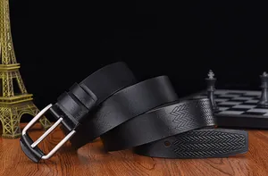 Detail of black leather men's belt with silver pin buckle and embossed woven texture