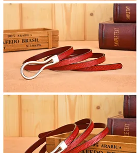 Detail of red pebbled leather belt with silver ring buckle on vintage wooden background