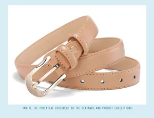 Detail of camel leather belt with heart-shaped rhinestone buckle and gold metal pin