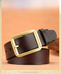 Detail view of men's leather belt with brushed gold buckle on a textured background