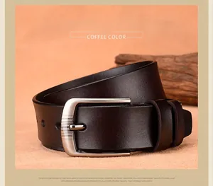 Detail of coffee brown leather belt with vintage brushed metal buckle on wood texture