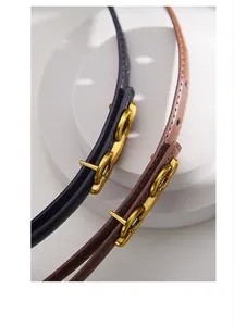 Detail of slim leather belts in black and brown with adjustable gold metal hook buckle