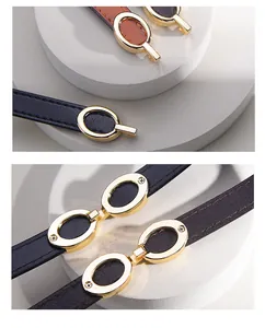 Detailed close-up of slim black and brown leather belts with gold oval metal buckles