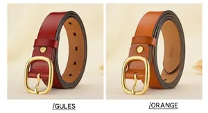 Primer plano de cinturones de cuero rojo y naranja con hebillas doradas sobre tela beige