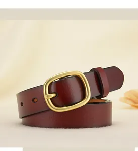 Gros plan d'une ceinture en cuir bordeaux avec boucle dorée polie sur un tissu beige