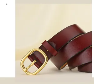 Détail macro d'une ceinture en cuir bordeaux avec boucle ovale dorée mate
