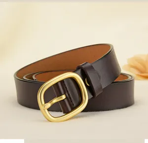 Détail d'une ceinture en cuir marron foncé avec boucle dorée mate sur tissu texturé