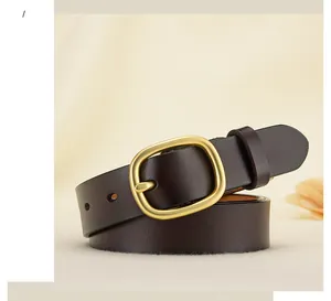 Détail d'une ceinture en cuir marron foncé pour femme avec boucle ovale dorée polie