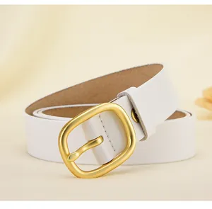 Détail de la ceinture en cuir blanc avec boucle en métal doré mat sur fond doux