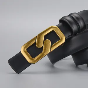 Women's black leather belt featuring a unique vintage gold geometric buckle on grey background