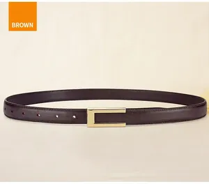 Detail of thin dark brown leather belt with elegant gold rectangular buckle on beige fabric